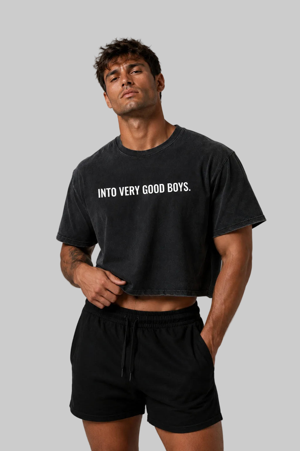 Man wearing a black t-shirt with text and black shorts on a gray background