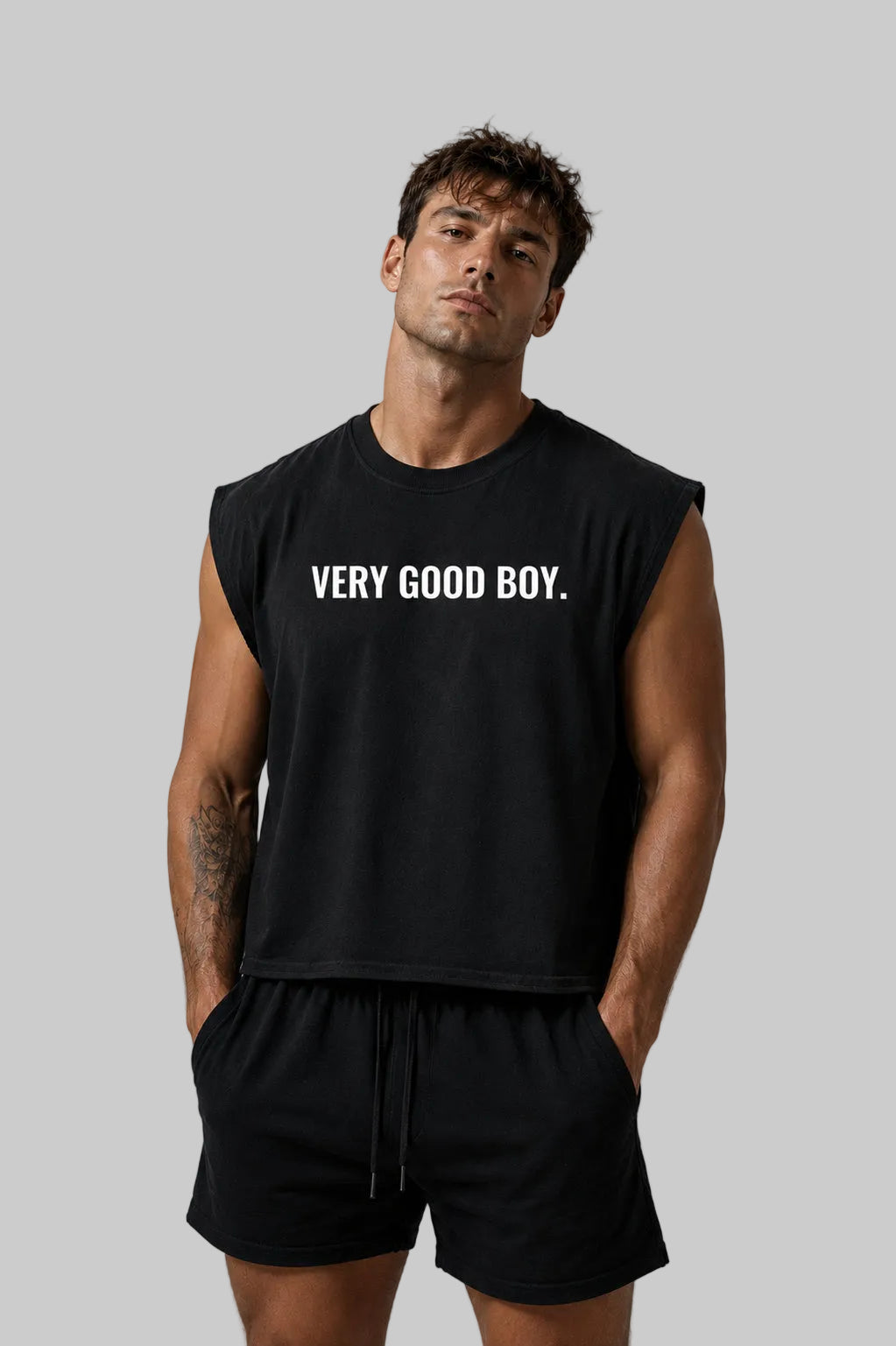 Man wearing a black sleeveless shirt with 'VERY GOOD BOY' text on a gray background